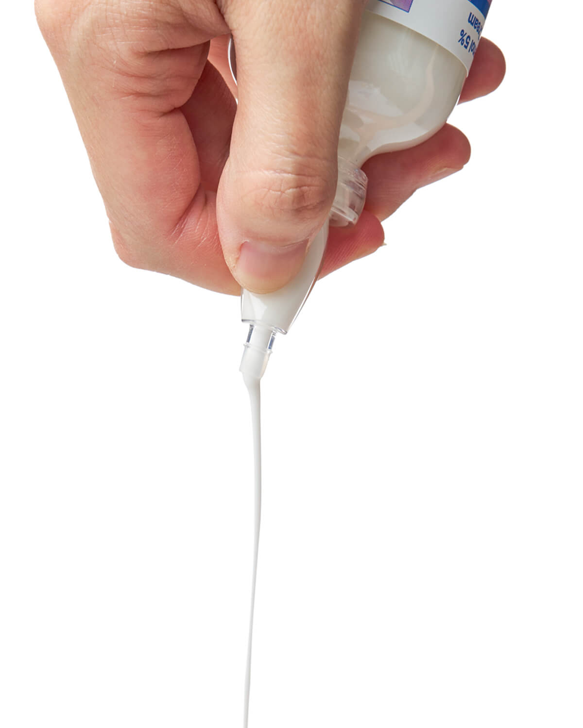 A hand holds the bottle upside down, dispensing a long, steady stream of the white, milky cream against a plain white background.
