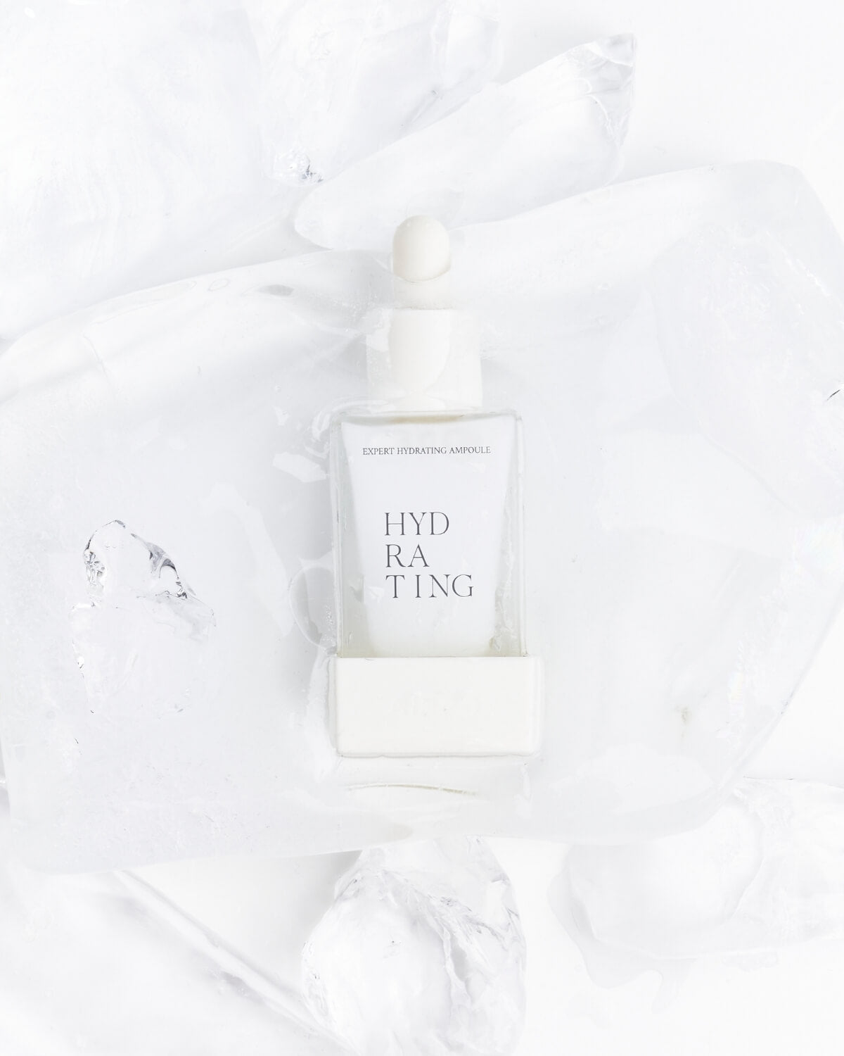 A composition of five clear, square, dropper bottles of the Aippo Expert Hydrating Ampoule scattered across a white surface, with a thin layer of the blue liquid smeared across the background.