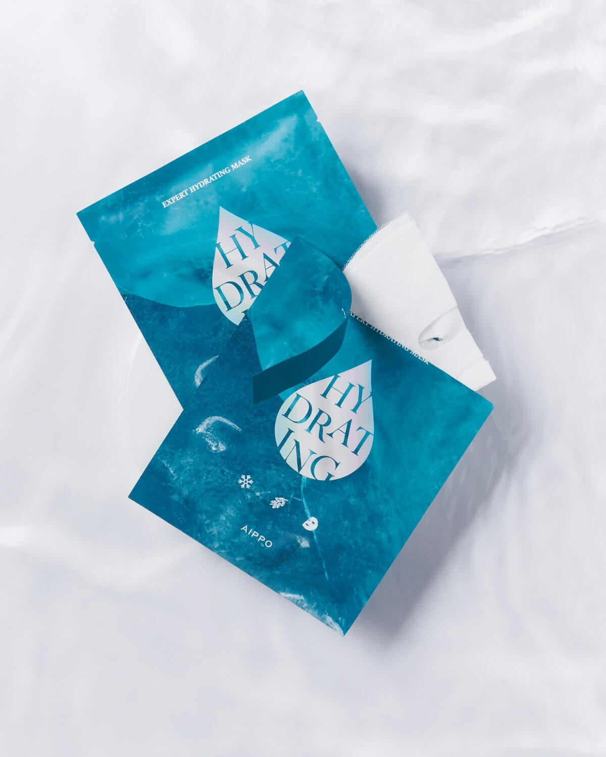 Two AIPPO Expert Hydrating Mask packets on a white silky background. Intense moisture sheet masks for skin relief.