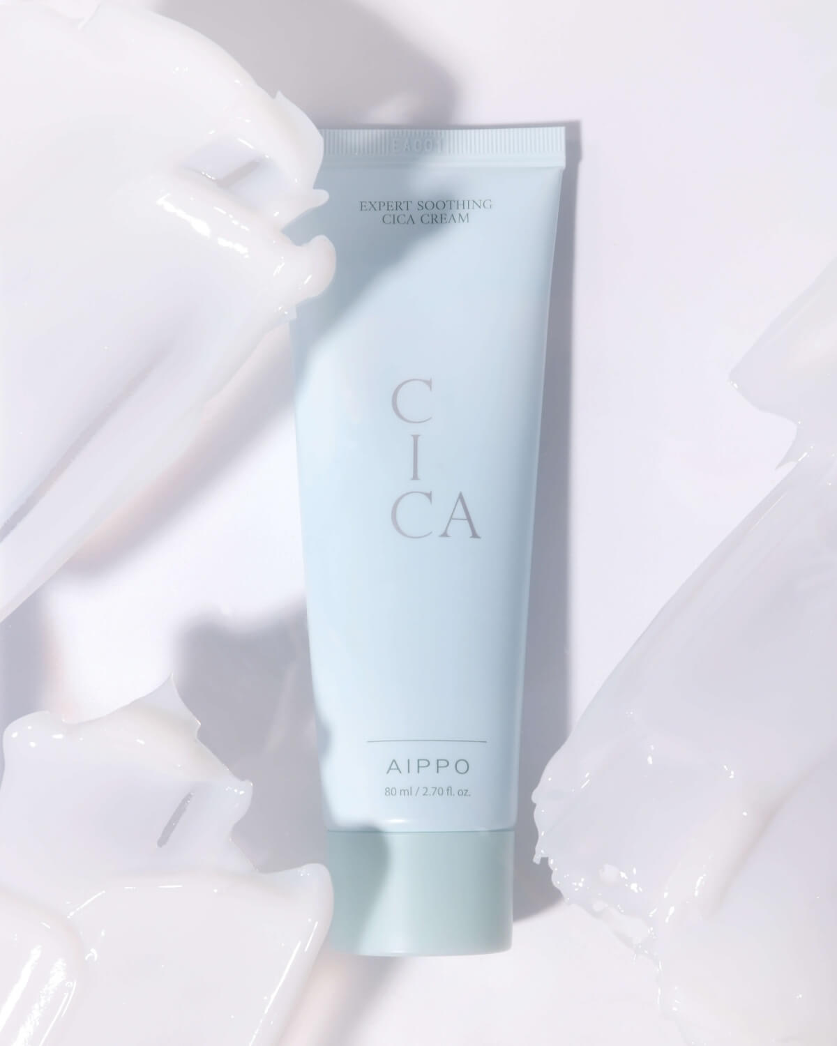 The Cica Cream tube is centrally placed, framed by thick swirls of the white cream product around it, giving a dynamic, textural close-up against a white background.