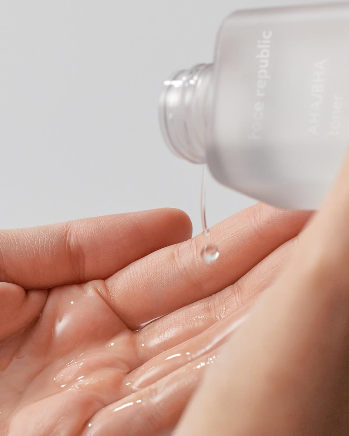 Clear liquid texture of the Face Republic AHA BHA Toner being poured into a palm.