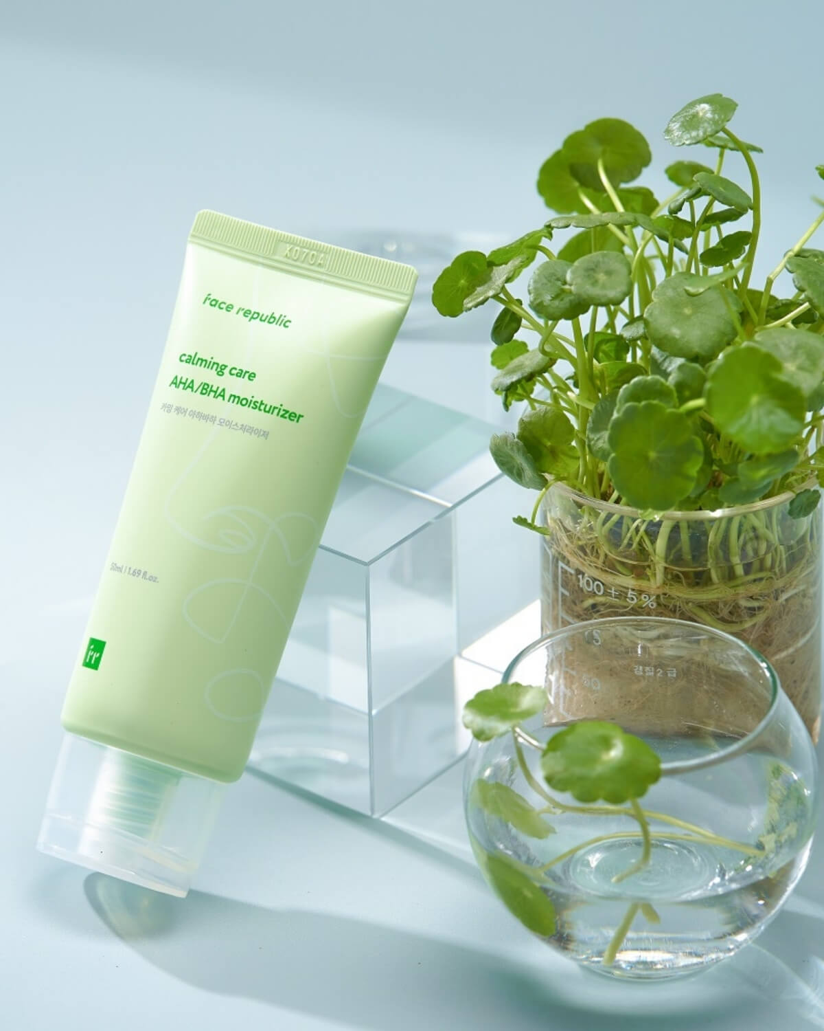 Face Republic Calming Care moisturizer tube leaning against glass blocks next to a green plant.