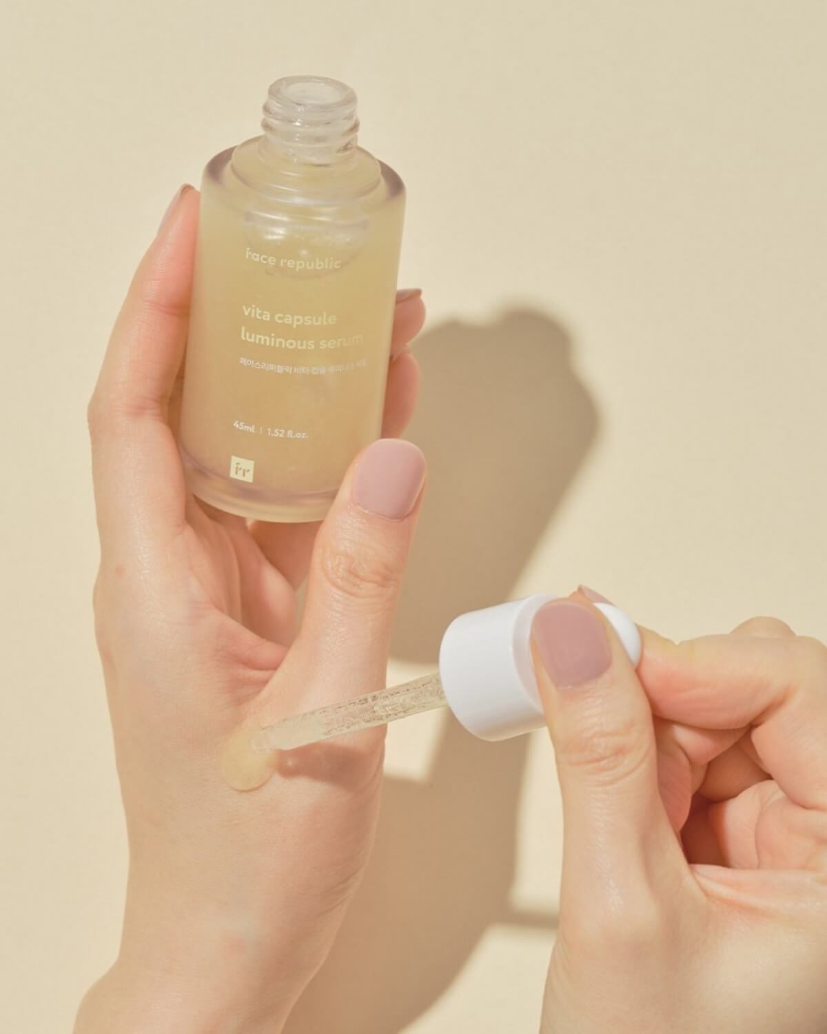 Applying Vita Capsule Luminous Serum texture onto a hand using a glass dropper.