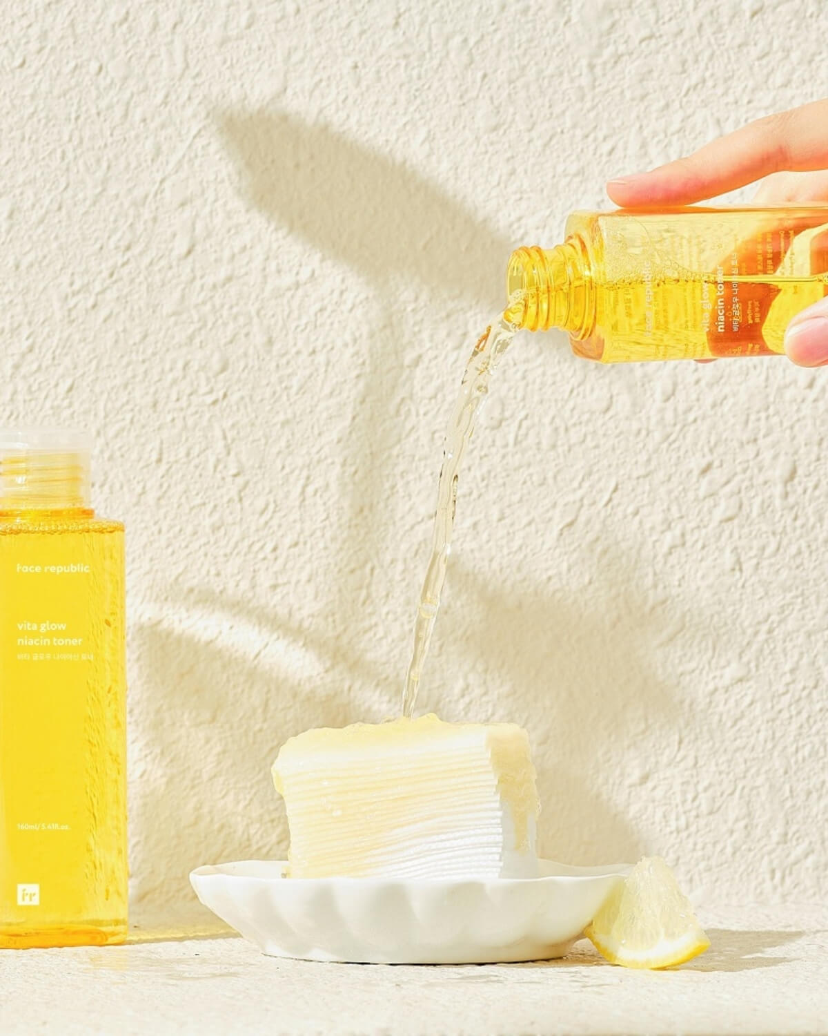 Pouring Face Republic Vita Glow Niacin Toner onto a stack of cotton pads.