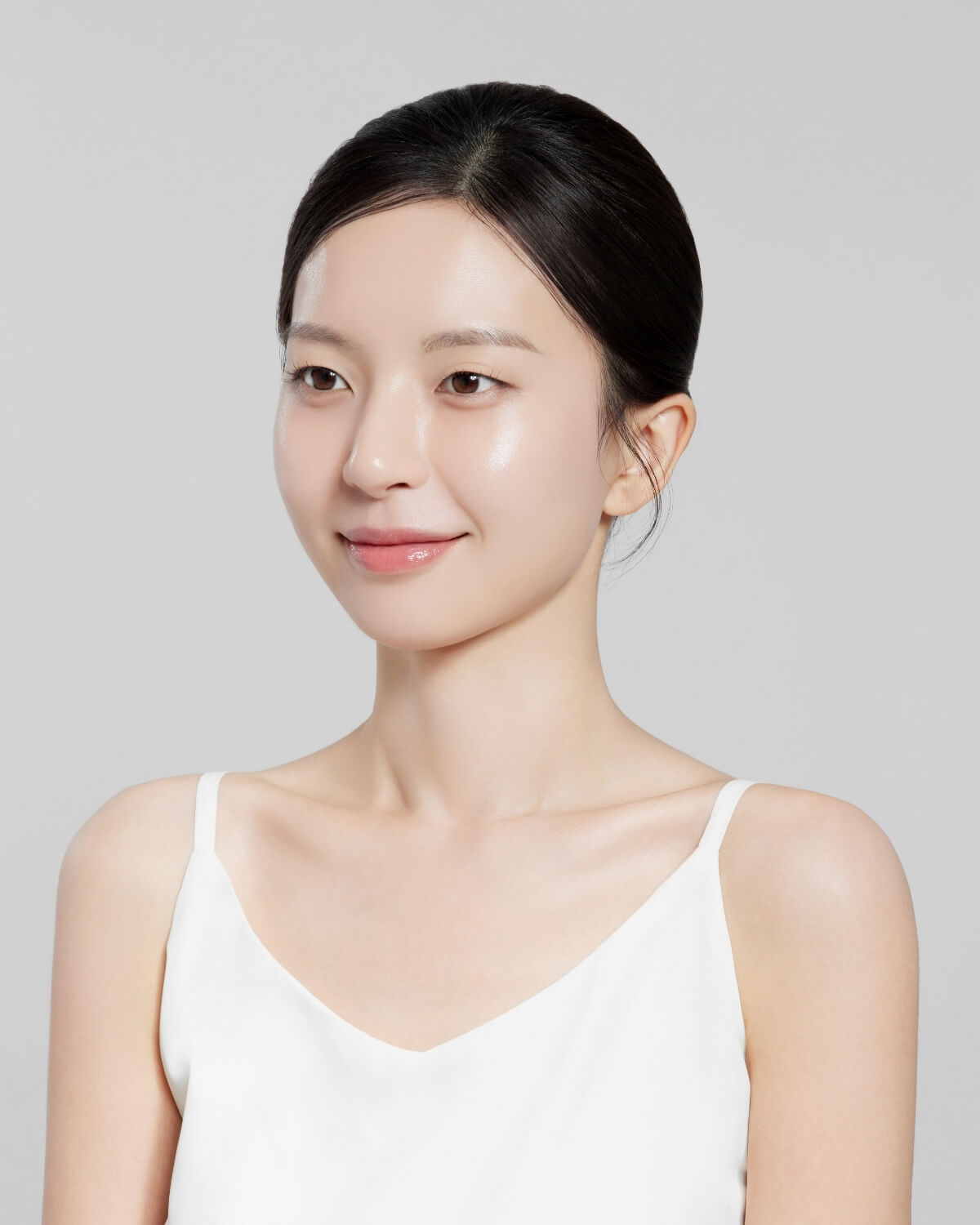 Portrait of a woman with radiant, hydrated skin smiling against a neutral background.