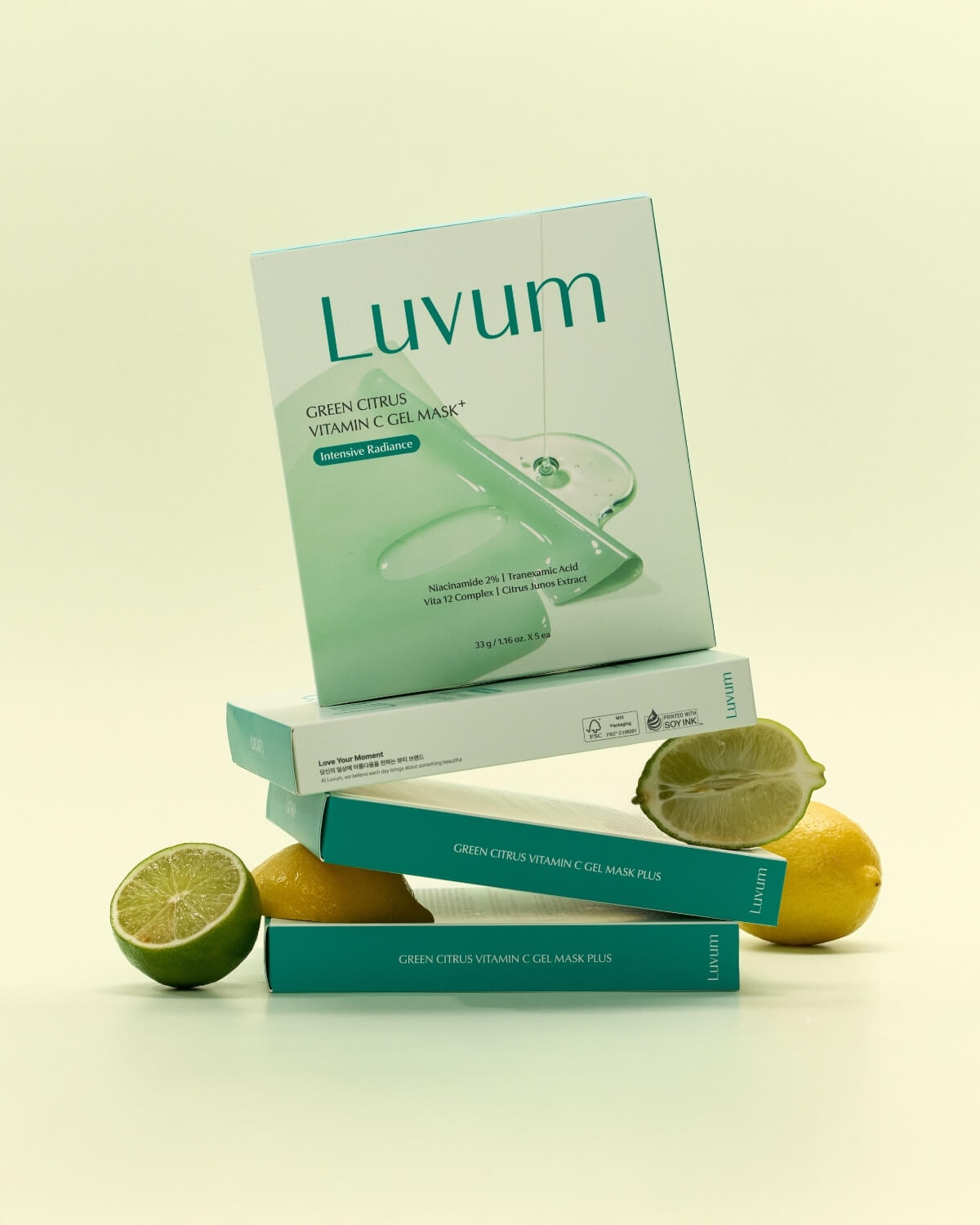 Stacked Luvum Green Citrus Vitamin C Gel Mask boxes displayed with fresh cut lime halves and whole yellow lemons.