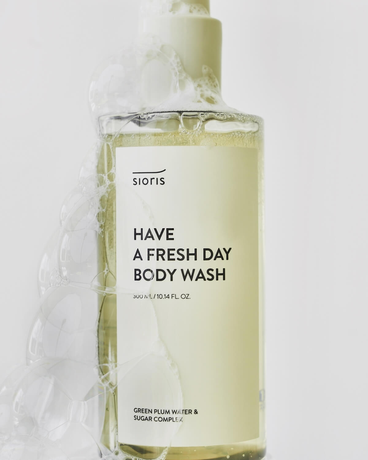 Close-up of Sioris Have a Fresh Day Body Wash clear bottle covered in rich soap suds and bubbles.