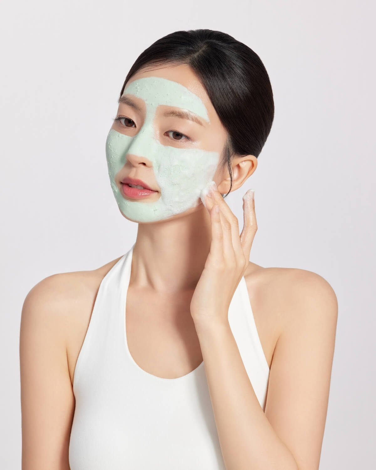 Woman massaging lathering green Dr. Ceuracle Jeju Matcha Clay Mask Cleanser across her face.