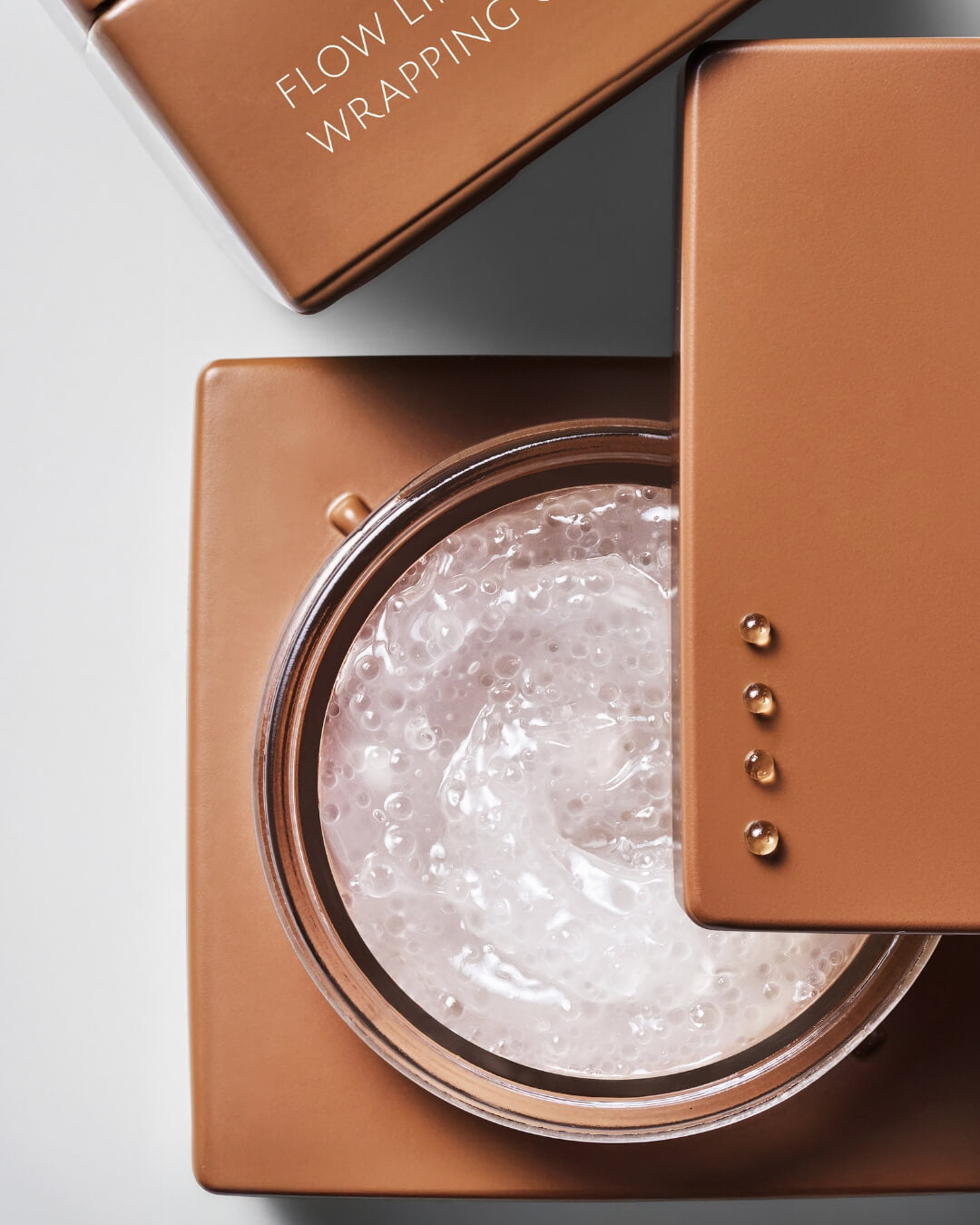 Top view of an open jar of Koy Flow Lifting Wrapping Cream revealing its hydrating capsule gel texture.