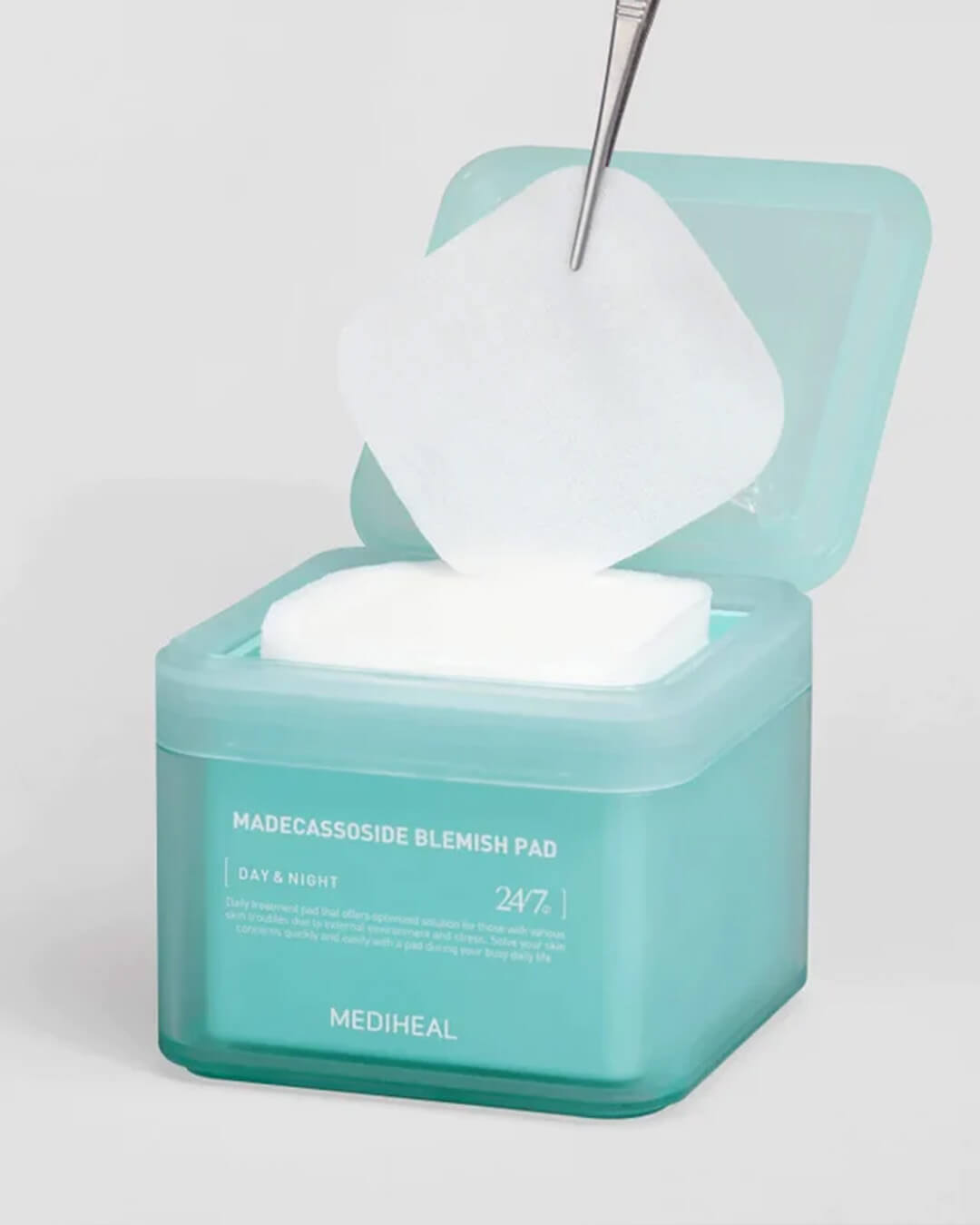 Tweezers lifting a square cotton pad from the open Mediheal Madecassoside Blemish Pad tub.