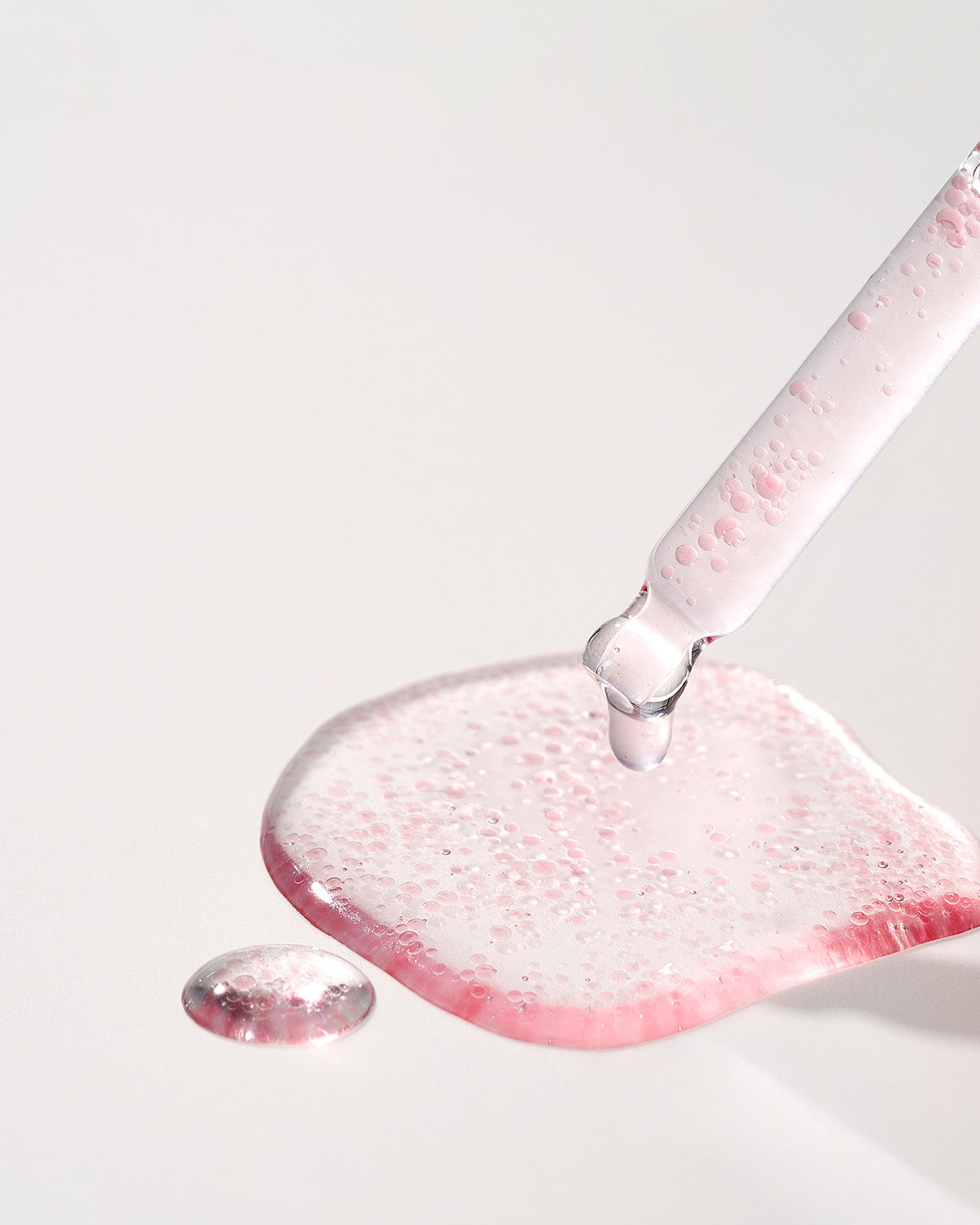 Close-up of a glass dropper dispensing pink, bubbly Purito Multi PDRN Collagen EGF Serum.