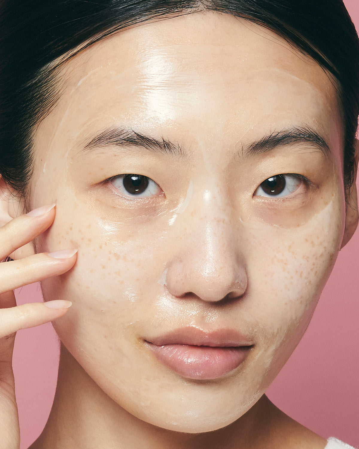 Close-up of a woman's face with the Purito Multi PDRN Collagen Real Glow Mask drying into a clear film.