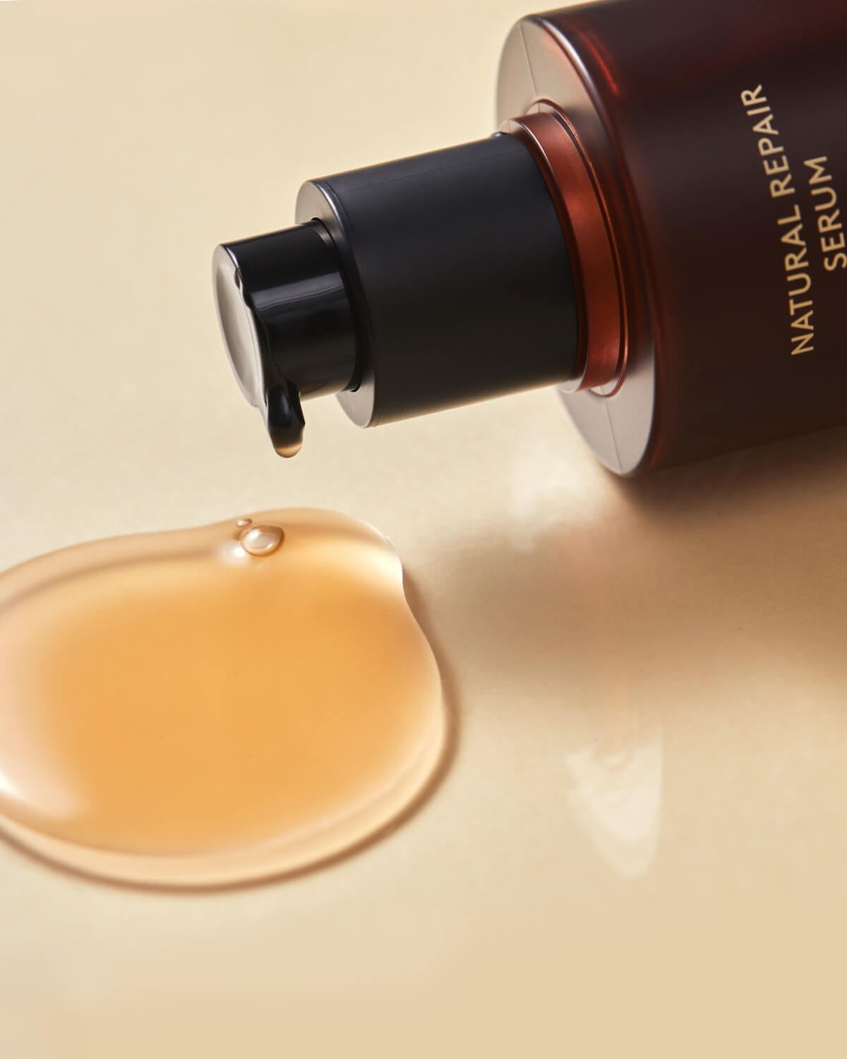 Close-up of a drop of Natural Repair Serum vitalizing red ginseng essence dripping from the pump onto a surface