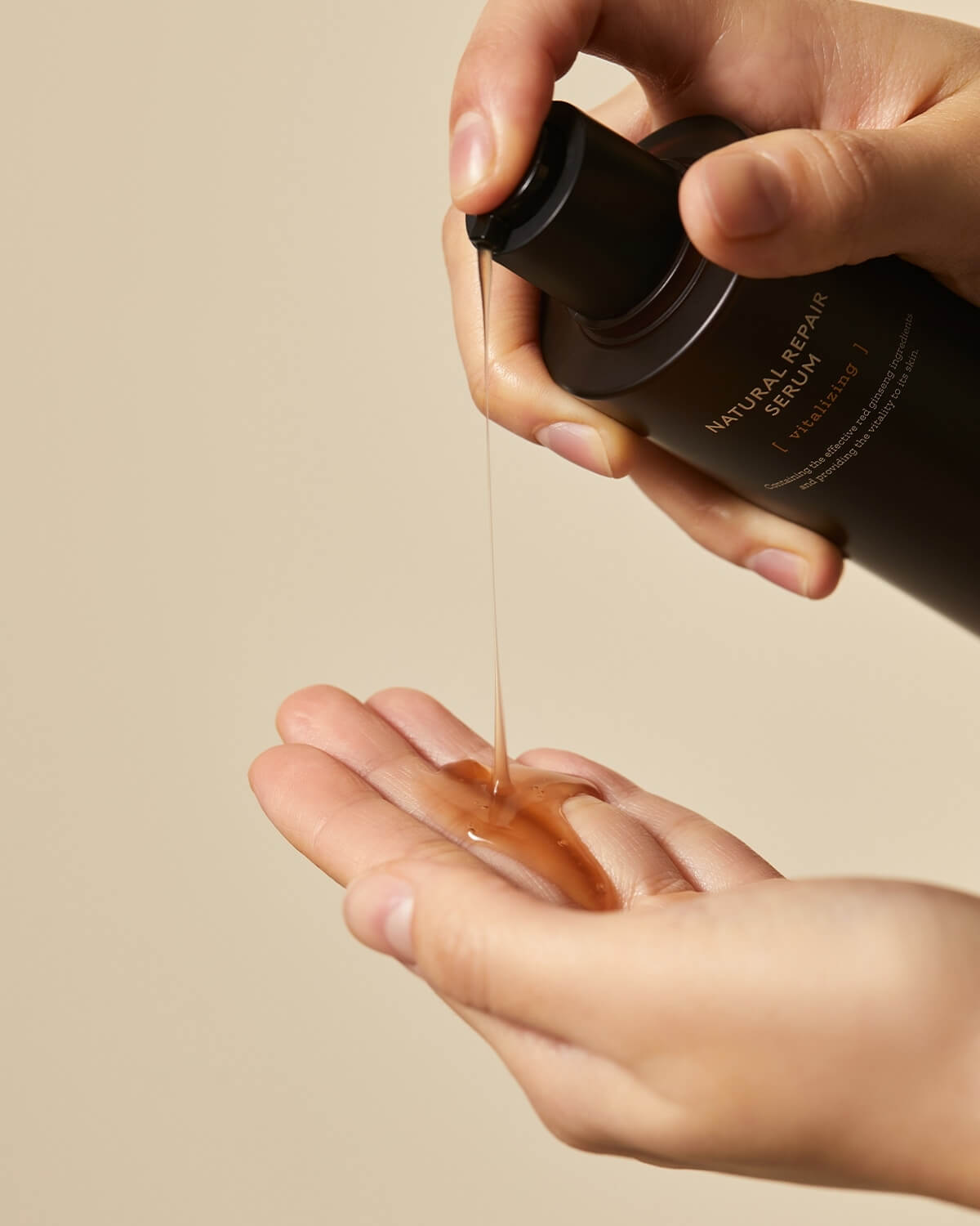 Hand dispensing Natural Repair Serum with vitalizing red ginseng onto the palm. Moisturizing Korean skincare.
