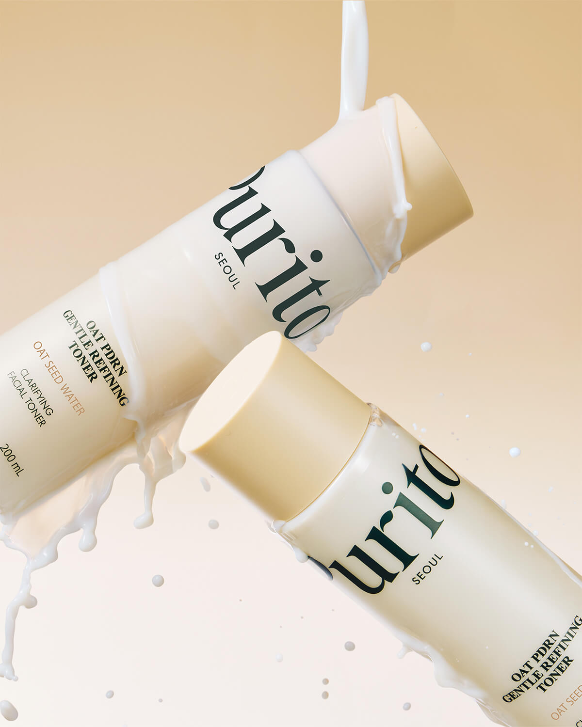 Two bottles of Purito toner tilted diagonally with a milky white liquid splashing over them against a beige background.