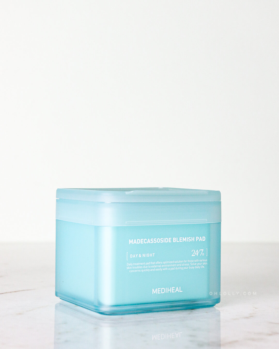 Closed light blue container of Mediheal Madecassoside Blemish Pad sitting on a white marble surface.