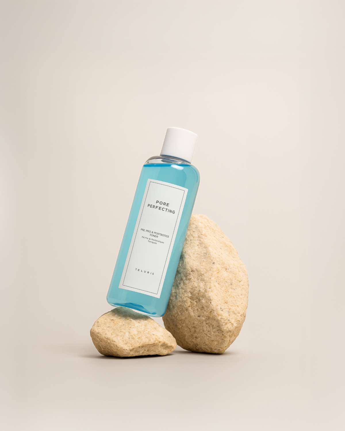 Teluris Pore Perfecting Toner bottle leaning against natural stones for a minimalist aesthetic.