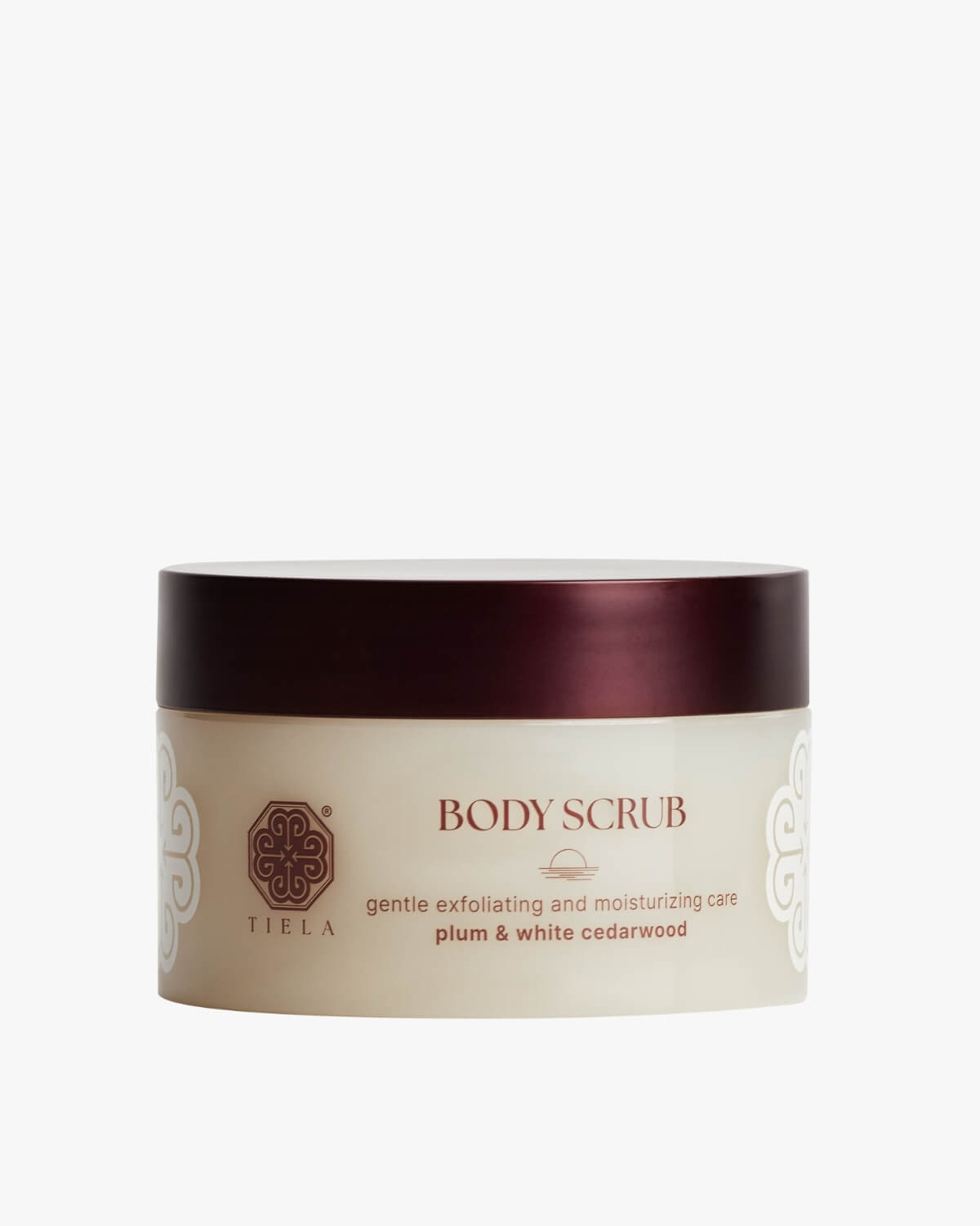 Front view of a round Tiela Body Scrub jar in a neutral beige with a deep red lid, labeled "gentle exfoliating and moisturizing care plum & white cedarwood."