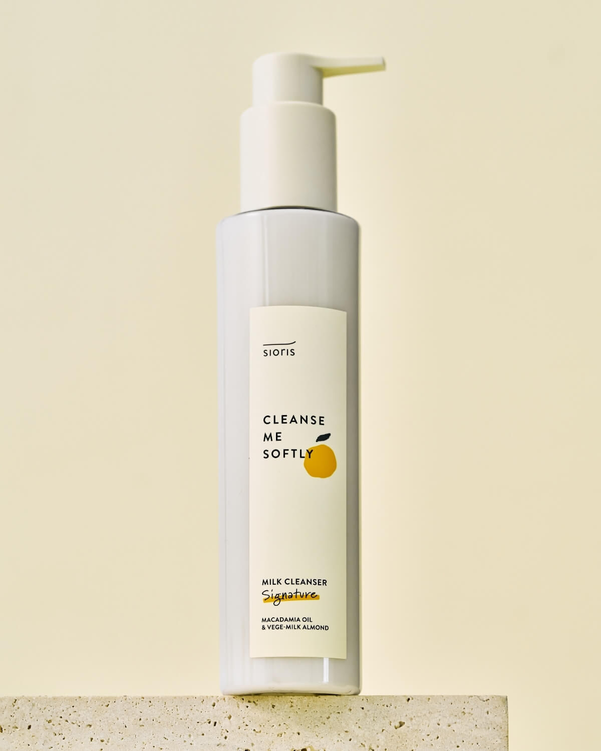 Sioris milk cleanser bottle standing on a stone textured block.