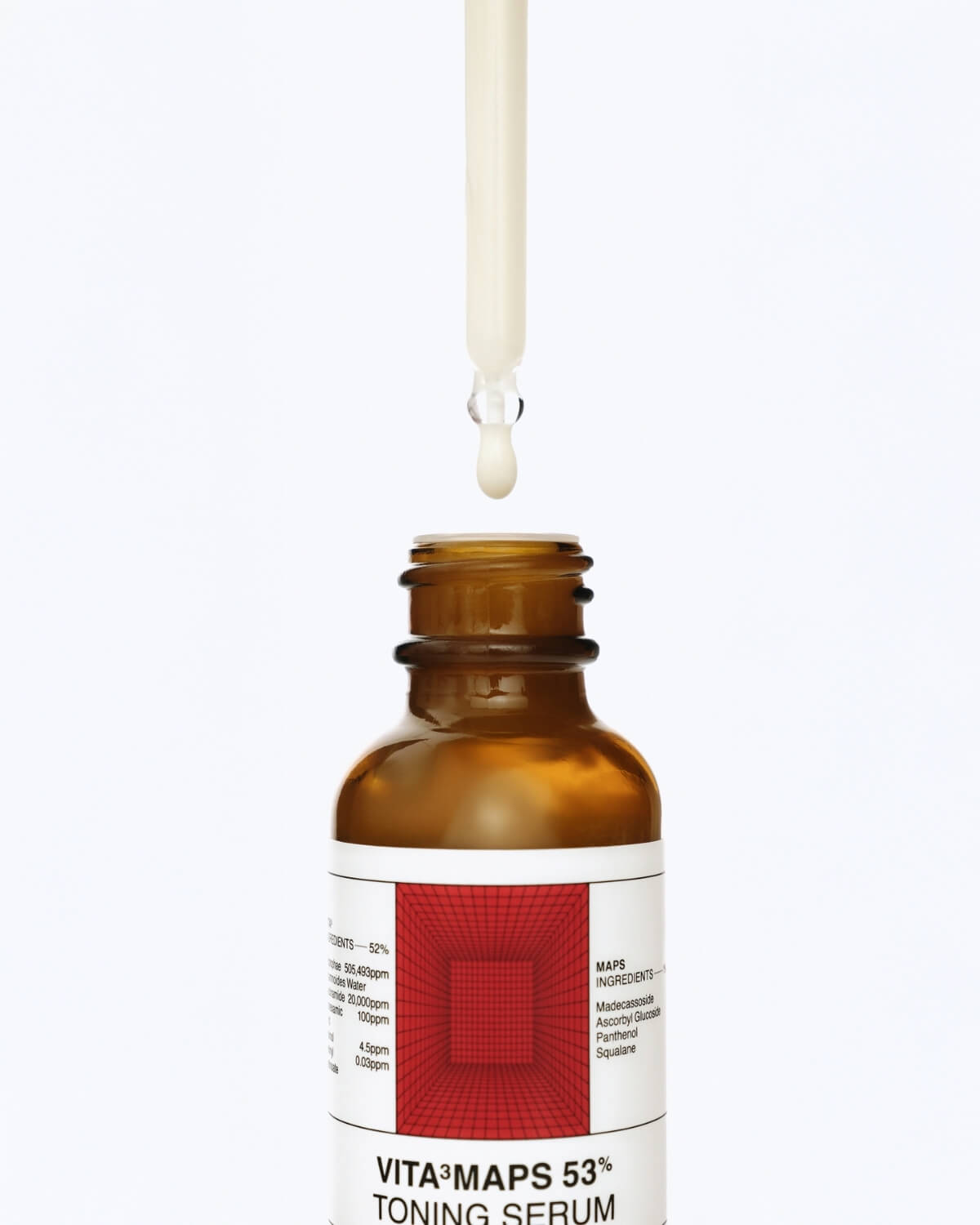 A close-up of a brown glass serum bottle with a white and red label. A white dropper is suspended above the opening, with a single drop of pale yellow serum about to fall into the bottle.