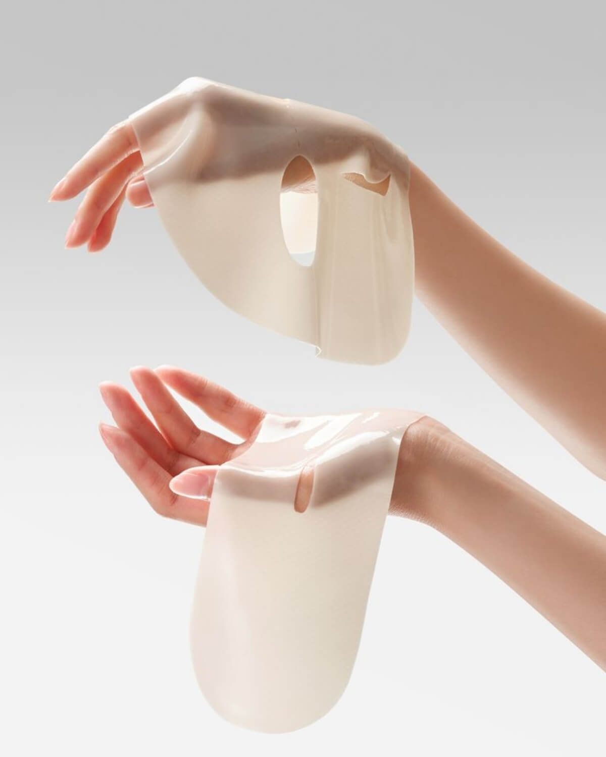 Close-up of a person holding the translucent, milky-colored Vegan Kombucha Tea Essence hydrogel mask sections.