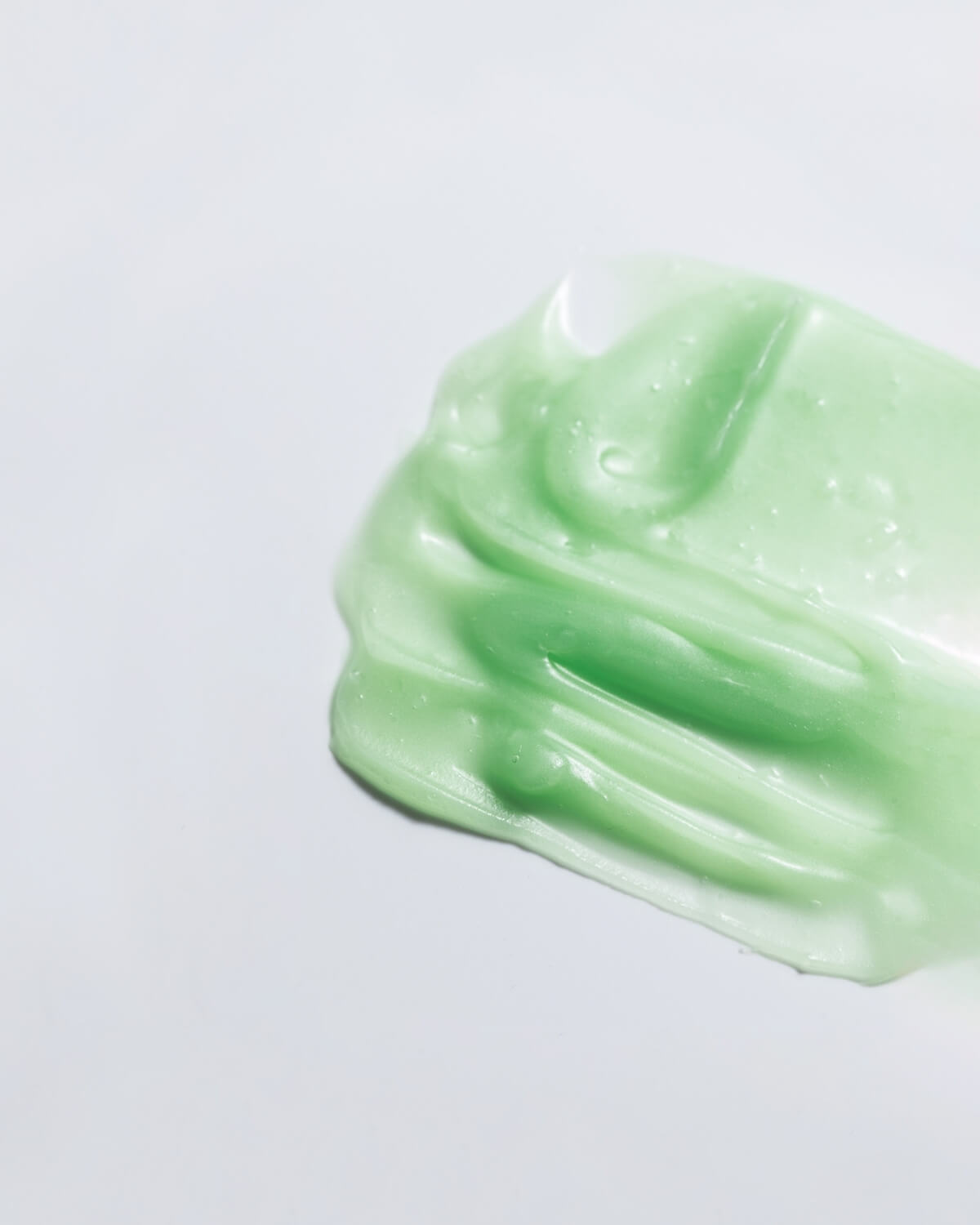 Texture shot of WYLYS Phyto Green Cleansing Balm showing its semi-transparent green gel-to-oil consistency.