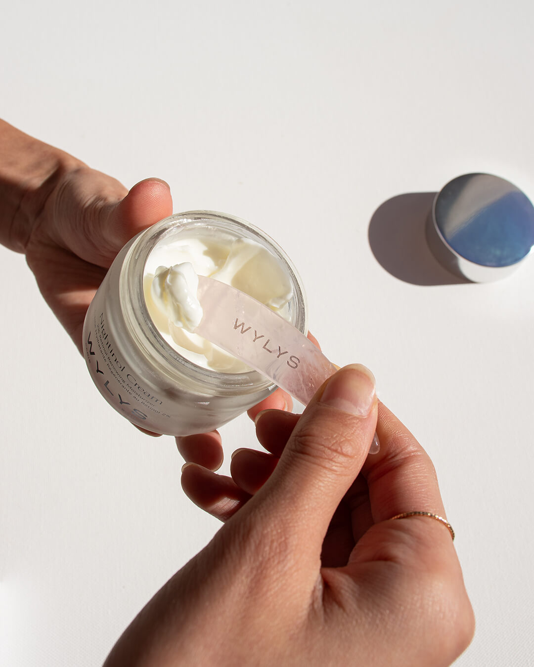 WYLYS Nightinol Cream with Rose Quartz Spatula Facial Tool Demo, Hands scooping cream out of Nightinol jar with pink spatula 