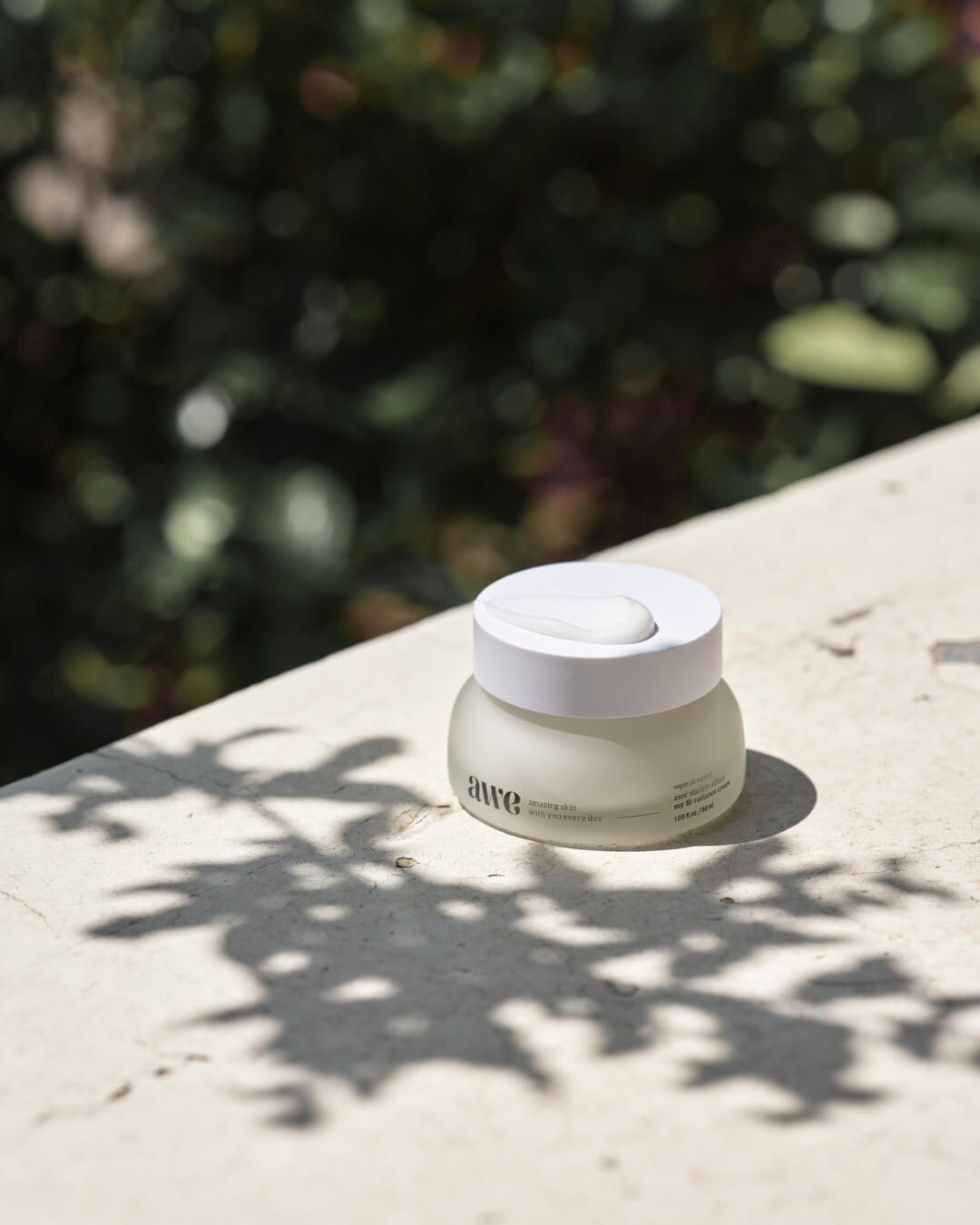 Awe natural face radiance cream jar resting outdoors on a stone surface under sunlight.