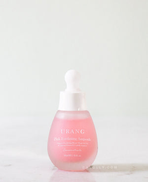 The Urang Pink Everlasting Ampoule in a frosted pink glass dropper bottle with a white cap, sitting on a white, slightly reflective marble surface.