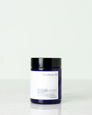 Front-on studio shot of the Pyunkang Yul Balancing Gel jar. The dark blue glass jar has a simple white label and stands upright on a pale background, emphasizing its unique honey-like texture and anti-aging benefits.