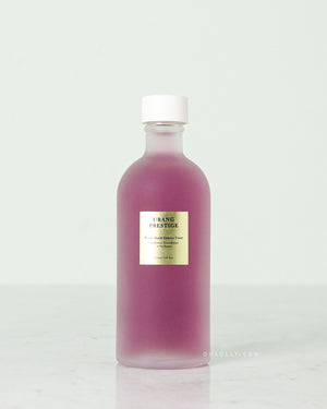 The Urang Prestige Purple Shield Essence Toner in a frosted glass bottle, showcasing the vibrant purple liquid inside, with a small gold-and-white label.